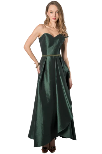 Woman in a dark green velvet strapless evening gown with a beaded belt, posing with one hand on hip and wearing gold jewelry.