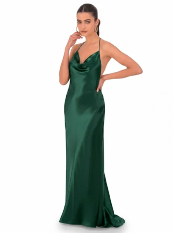 Woman in an emerald green satin halter gown, posed with one hand near her face and the other on her hip against a white backdrop.
