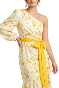 Woman wearing a white floral dress with yellow flowers and a yellow sash belt.