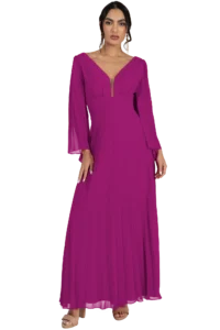 Woman modeling a magenta floor-length pleated gown with a plunging V-neck, long sheer sleeves, and drop earrings.