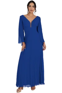 Woman in a royal blue, floor-length pleated gown with a deep V-neck and long sleeves, standing against a neutral background with minimal accessories (earrings) and nude sandals.