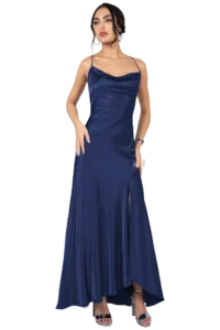 Woman in a navy satin evening gown with thin straps, standing with one hand on hip and wearing silver heels and jewelry.