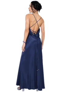 Woman wearing a navy satin backless gown with crisscross straps, seen from behind, hair up and wearing earrings on a black background.