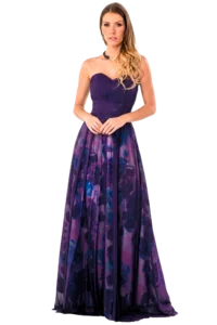 Woman in a long purple strapless gown with a gradient floral skirt, standing with hands clasped.
