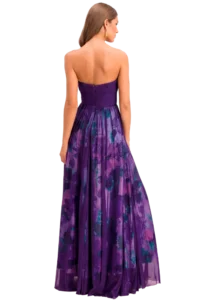 Back view of a woman wearing a strapless purple evening gown with a sheer, floral-patterned skirt.