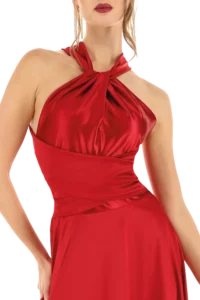 Woman wearing a red satin halter-neck evening dress with a twisted front knot.