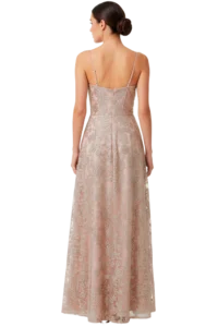 Back view of a woman in a pale pink lace evening gown with thin straps, standing against a black background.