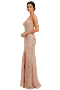 Woman in a blush pink lace evening gown with spaghetti straps, standing in profile and a thigh-high slit visible at the ankle.