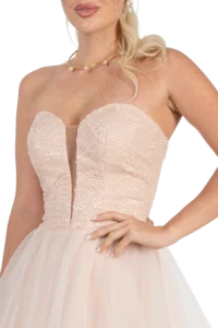 Close-up of a woman in a blush strapless beaded wedding gown with pearl jewelry, showing the bodice and jewelry.
