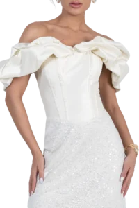 Woman wearing an off-the-shoulder white dress with large ruffled sleeves, close-up of upper body