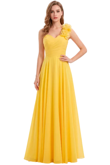Fashion model in a bright yellow, floor-length gown with a ruched bodice and a large floral appliqué on the right shoulder, standing with one hand on her hip.