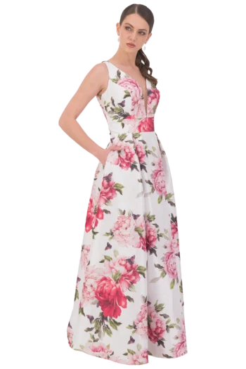 Model wearing a sleeveless white floral gown with large pink flowers, standing with one hand on the hip.