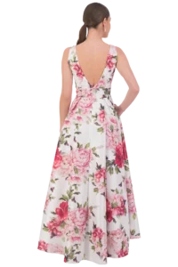 Woman seen from behind wearing a white floral dress with pink peonies and green leaves, her hair in a low ponytail.