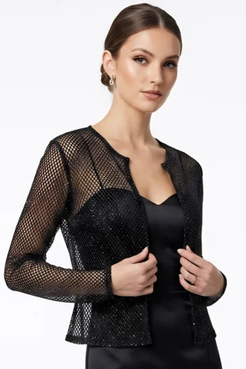 Portrait of a woman wearing a black mesh jacket over a black dress, looking at the camera with a calm expression.