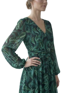Person wearing a dark green dress with a tropical leaf pattern, standing with one hand on hip (side view).