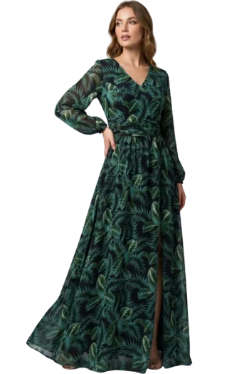 Woman wearing a floor-length dark green tropical leaf print dress with sheer sleeves, standing with one hand on her hip.