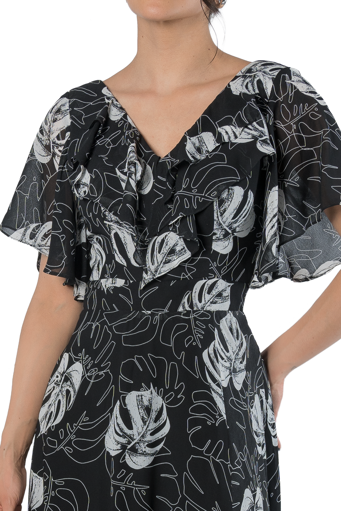 Woman wearing a black dress with a white abstract leaf print and a ruffled V-neck front.