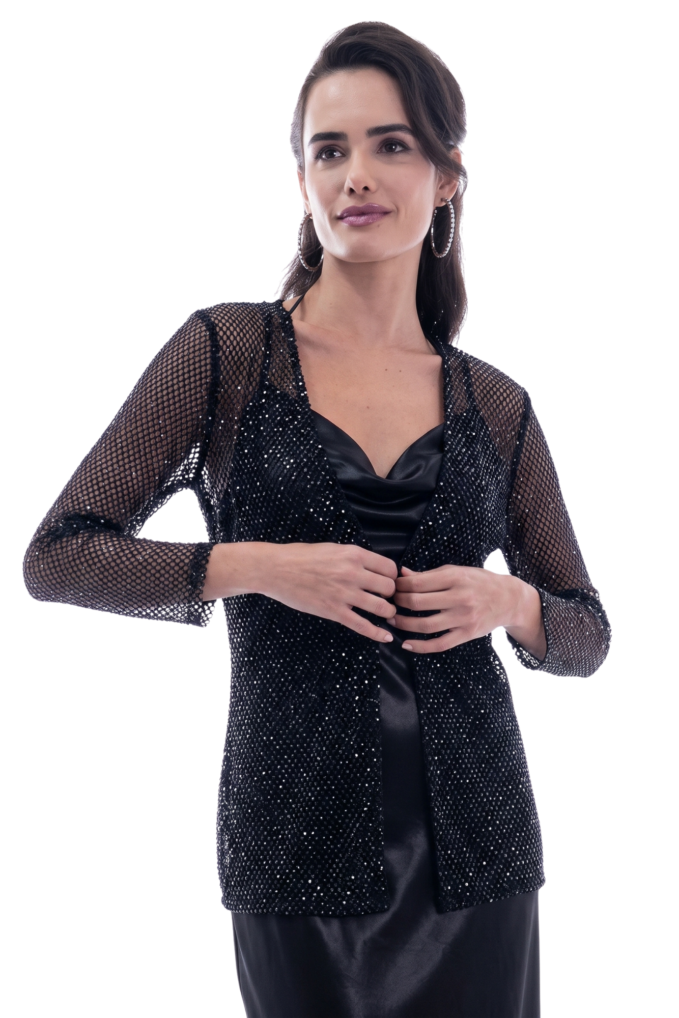 Woman posing in a black sequined mesh jacket over a satin black dress, adjusting the front with her hands.