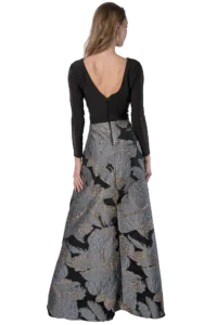 Woman seen from the back wearing a black long-sleeve top with a low back paired with a high-waisted, metallic floral skirt.