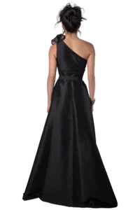 Back view of a woman in a black satin one-shoulder evening gown with a fitted waist and flowing train. Her dark hair is styled in an updo with hoop earrings.