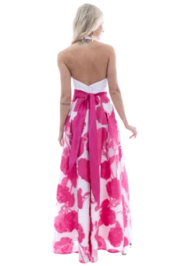 Back view of a blonde woman wearing a white strapless dress with a pink floral skirt and a pink sash tied at the waist.