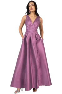 Full-length view of a woman in a mauve satin evening gown with a plunging V-neck and pockets, posing with hands in pockets.