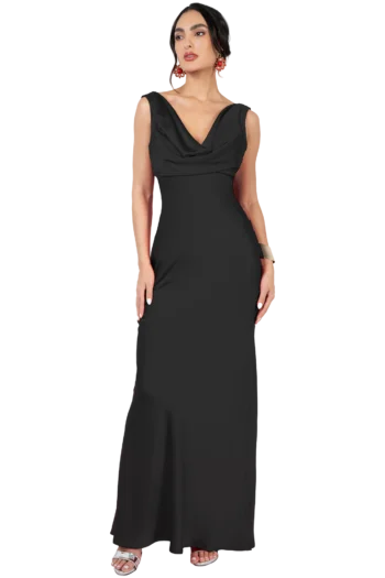 Woman in a long black evening gown with a draped neckline and matching accessories, standing with hands at her sides.