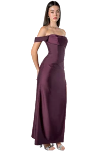 Woman wearing a burgundy off-the-shoulder evening gown with a jeweled necklace and silver sandals, posing gracefully.