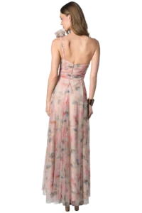 Back view of a woman in a pastel pink floral one-shoulder dress with a ruched bodice and flowing skirt.