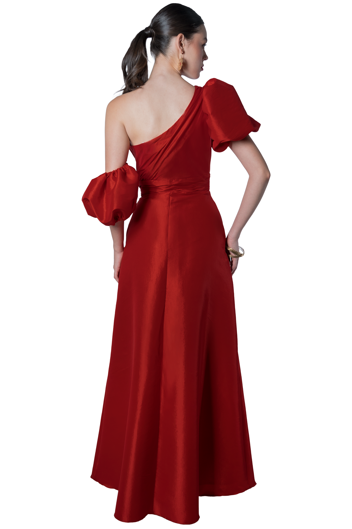 Back view of a woman wearing a red one-shoulder gown with a large puff sleeve on her left arm, her dark hair in a ponytail.