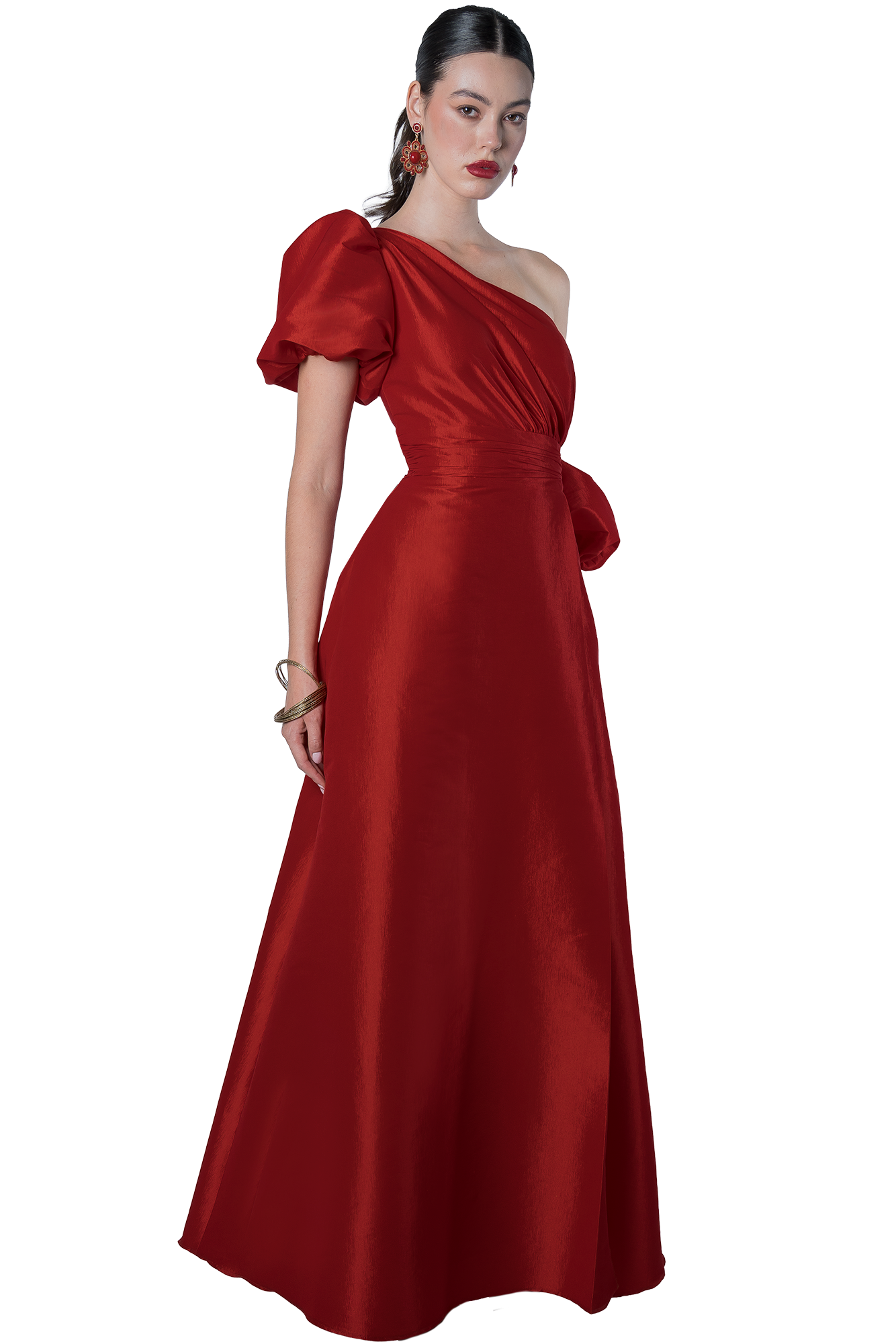 Woman in a floor-length red satin gown with a one-shoulder neckline and puff sleeve, wearing red lipstick and statement earrings.