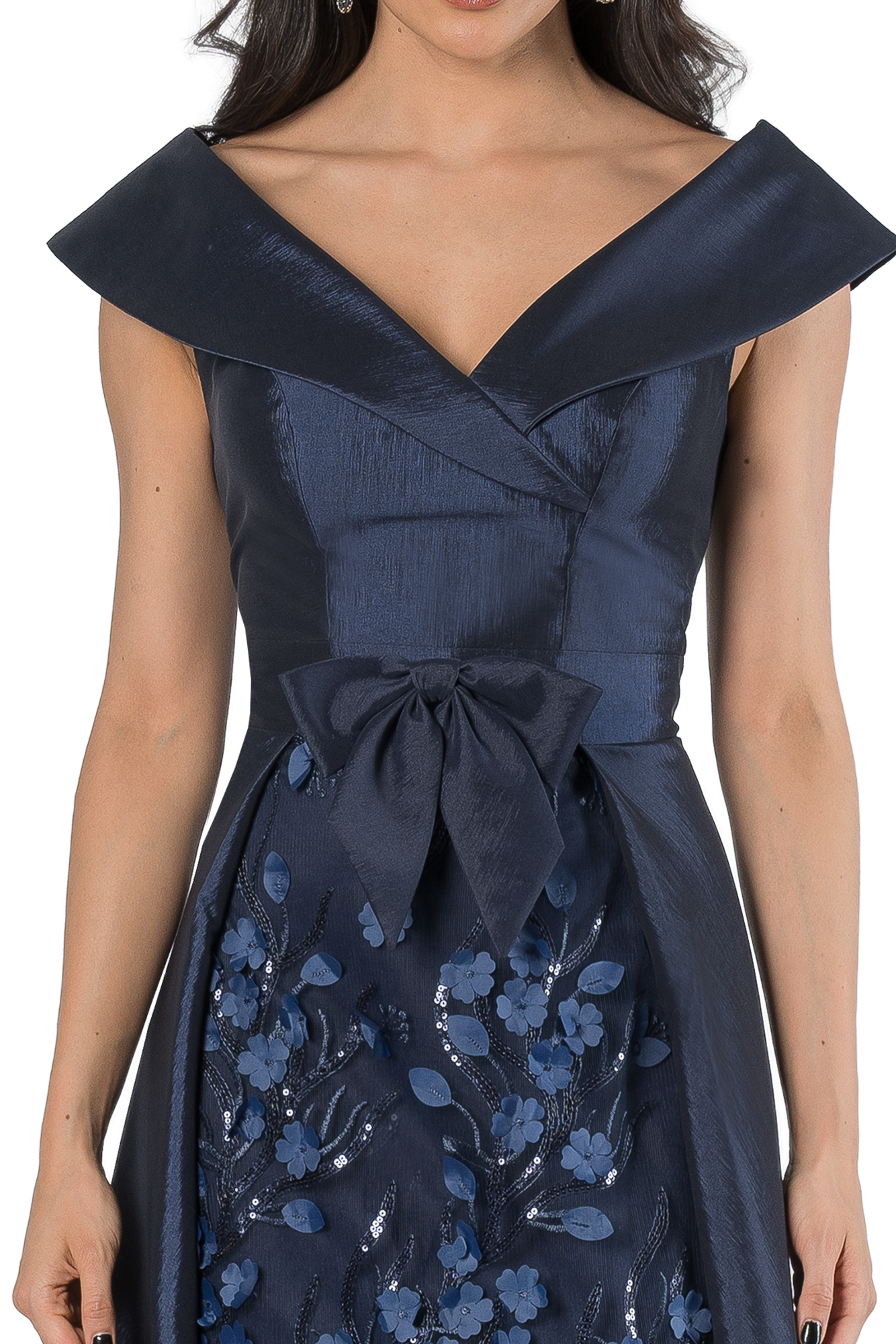 Close-up of a woman in a navy blue satin gown with a dramatic off-shoulder collar and floral-embroidered skirt piece near the waistbow area.