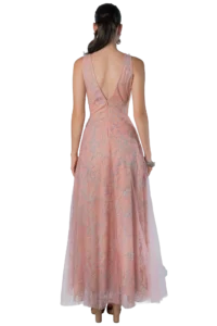 Back view of a woman in a pink, floor-length gown with silver floral embroidery and a V-shaped back, wearing silver earrings.",