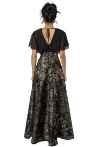 Back view of a woman in an elegant black dress with sheer flutter sleeves and a gold-flowered embroidered skirt, her hair in a bun.