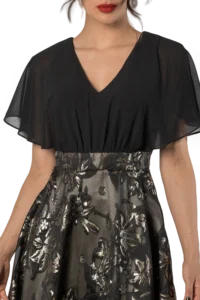 Woman wearing a black V-neck sheer blouse over a metallic floral dress, shown from shoulders down.