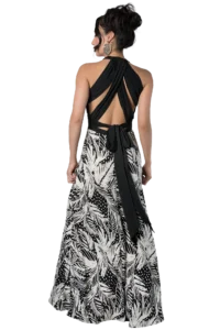 Woman seen from behind wearing a black halter top with a long sash and a black-and-white tropical leaf-patterned dress, updo hairstyle and large leaf-shaped earring