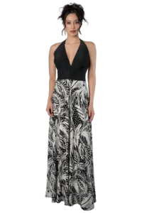 Woman in a black halter top and tropical black-and-white patterned maxi dress, standing and facing the camera.