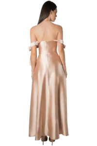 Back view of a woman in a peach satin off-shoulder evening gown with bow accents and high heels.