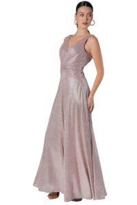 Woman in a blush-pink glitter evening gown, posing with a hand at her side and wearing hoop earrings against a black background.