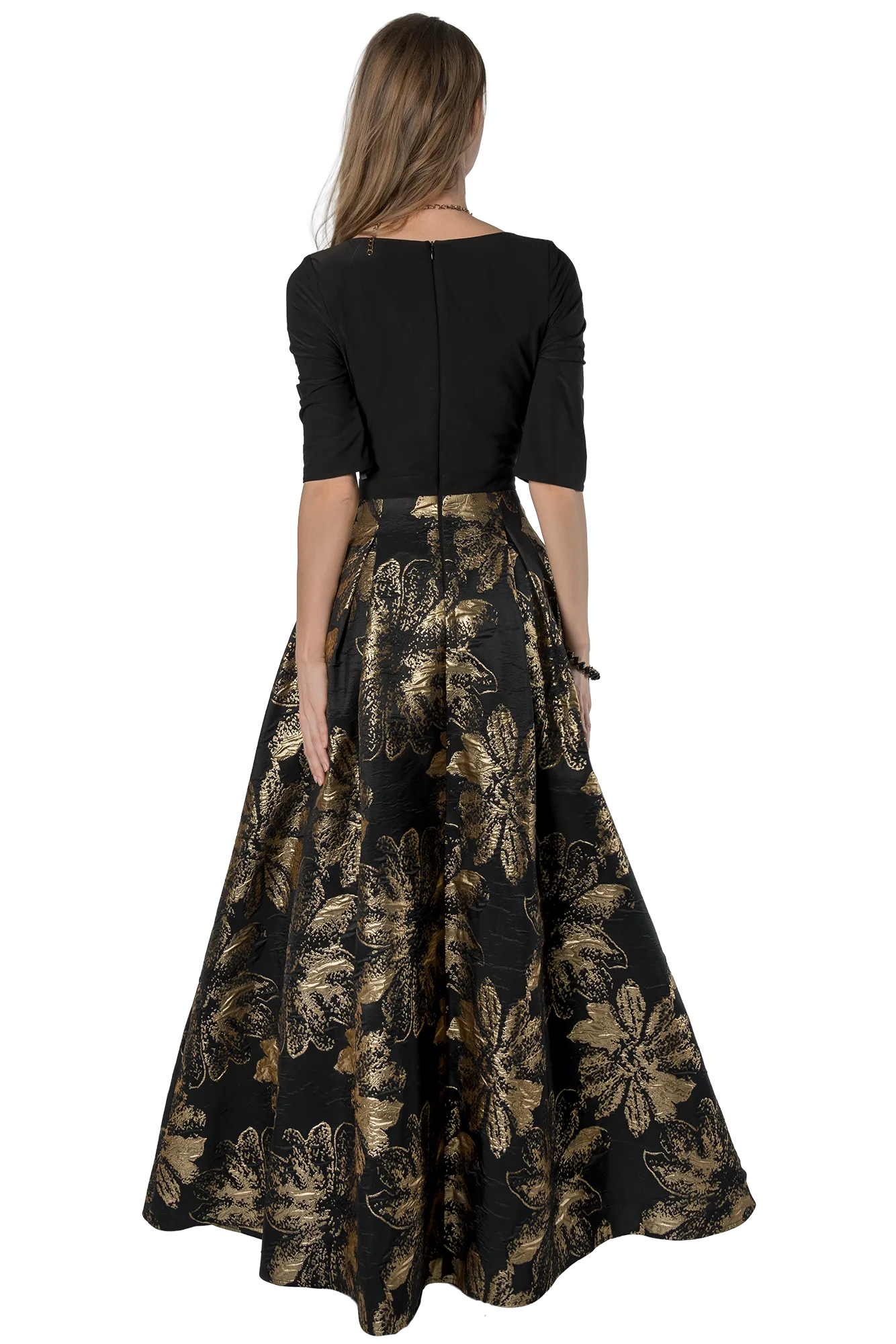 Back view of a person wearing a black short-sleeve top and a voluminous black and gold floral gown reaching the floor.