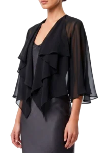 Woman wearing a black sheer blouse with cascading ruffles over a dark dress, shown from the chest down to the hips, on a black background.