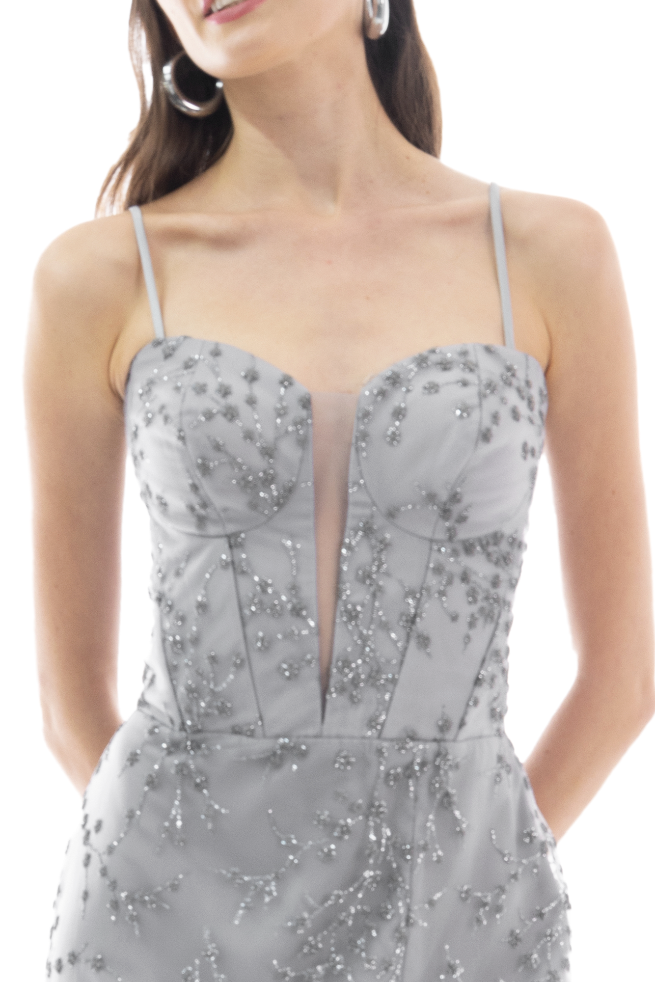 Person wearing a light gray beaded formal dress with a plunging neckline and hoop earrings.