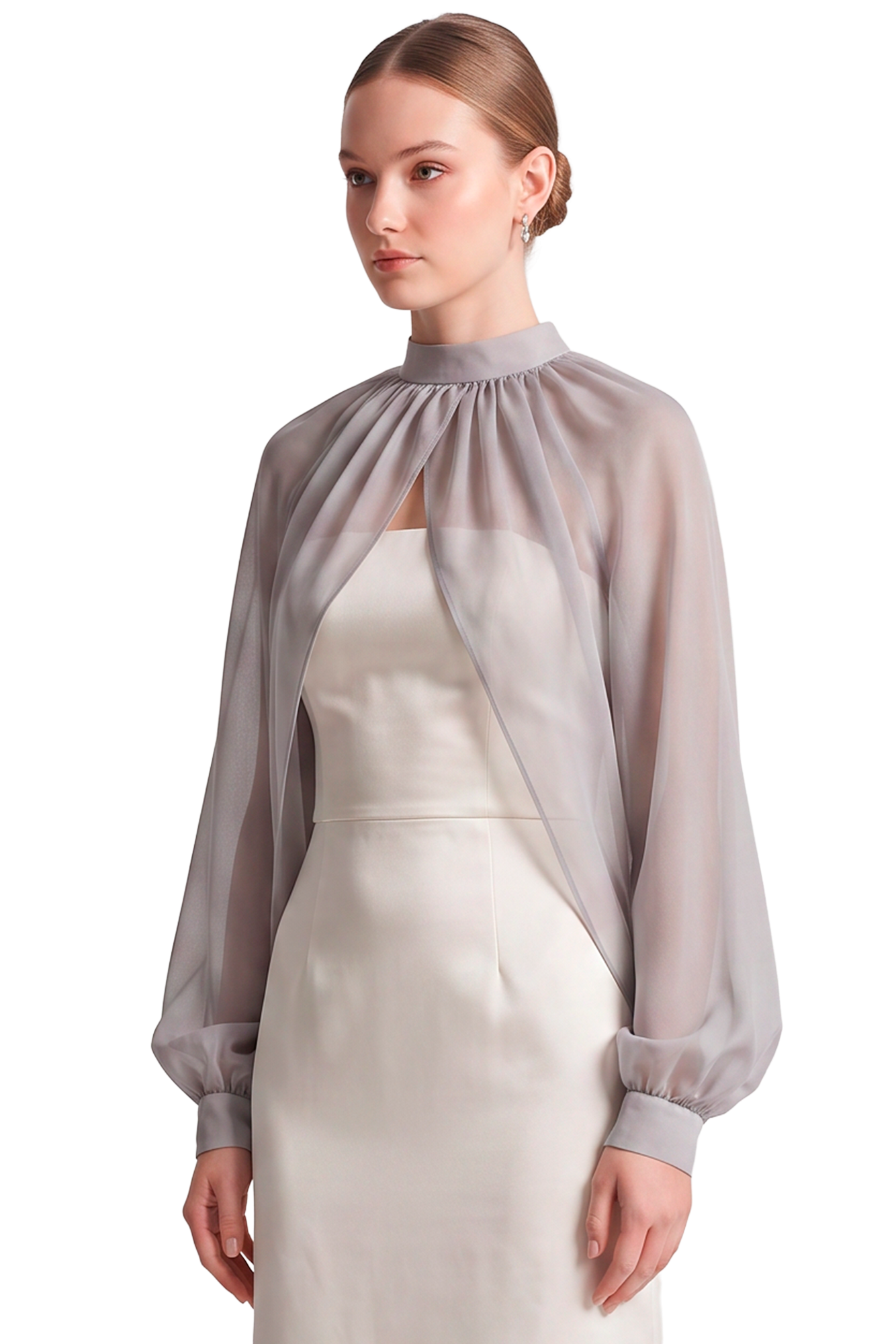 Woman in a pale satin evening gown with a sheer cape draped over her shoulders, standing against a black background.