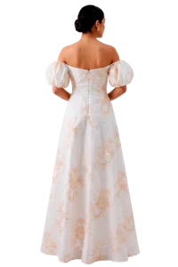 Back view of a woman in an off-the-shoulder white gown with peach floral pattern and a low bun, against a black background.