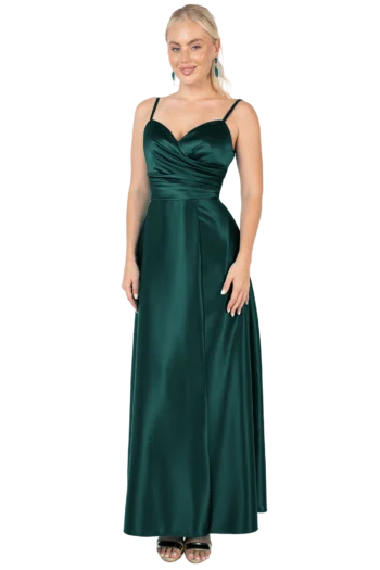 Full-length shot of a woman in an emerald green satin evening gown with thin straps, standing with her hands at her sides.