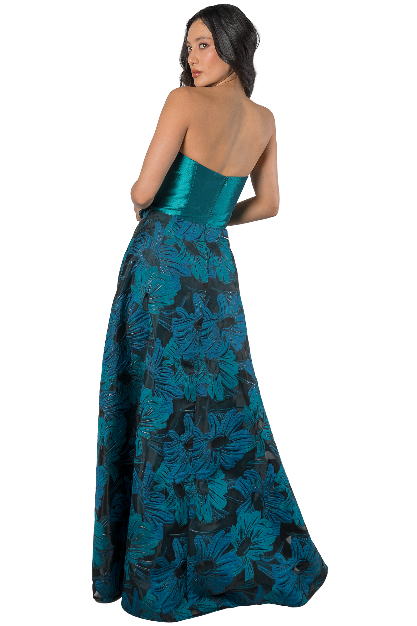 Back view of a woman wearing a turquoise strapless satin bodice and a blue floral maxi dress, posed with one arm bent